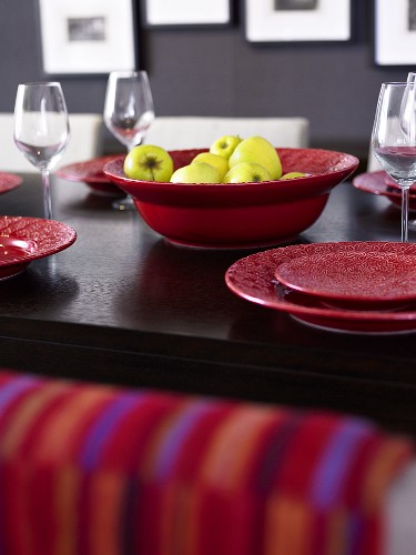 Bowl of apples on table with red tableware