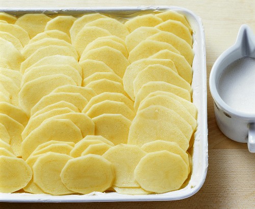 Potato slices arranged neatly in baking dish for gratin
