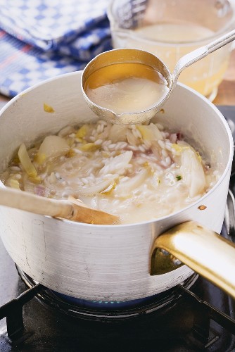 Risotto mit Chicorée zubereiten: Brühe nachgiessen