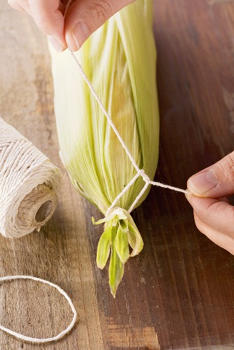 Leaves being tied around a corn cob