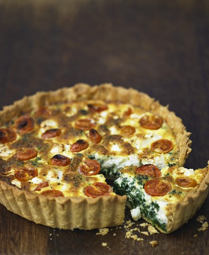 Cheese, spinach and tomato quiche, a piece cut