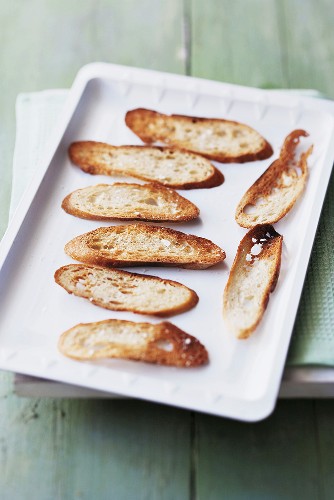 Grilled baguette slices on a baking sheet