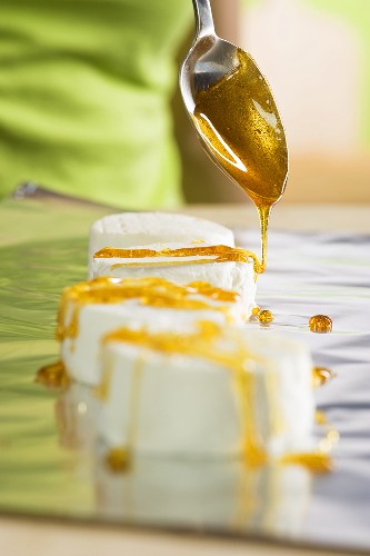 Fresh goat's cheese being drizzled with caramel