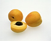 Two Whole Fresh Apricots; One Halved with Pit