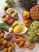 Skewered fish, vegetables and fruit, uncooked surrounded by fresh shrimp, fruits and vegetables