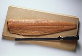 A Smoked Salmon Fillet on a wooden Cutting Board with Knife