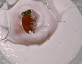 Strawberry falling into strawberry milk
