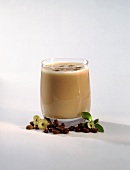 Cappuccino-Milchshake im Glas; Deko: Kaffeebohnen