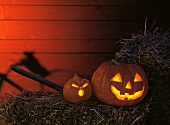 Two Jack o' Lanterns Lit with Candles on Hay