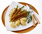 Several young glazed carrots with green stalk on plate