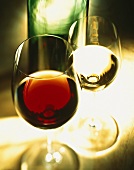 Rotweinglas vor Weissweinglas mit Flasche