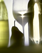 Shadow of a white wine glass, a pear & two bottles