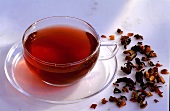 A cup of rose hip tea and a few dried rose hips