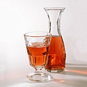 A glass of rose wine in front of a carafe 