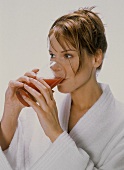 Junge Frau trinkt Tomatensaft aus hohem Glas