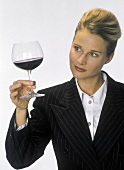 Junge Frau prüft Farbe von Rotwein in Stielglas
