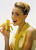 Junge Frau in gelber Bluse isst eine Banane