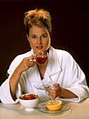 Frau beim Frühstück mit Tee, Cornflakes & Grapefruit