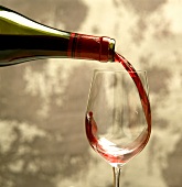 Junger Rotwein (Beaujolais) wird in ein Glas eingeschenkt