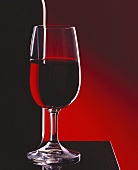 Stillleben mit Rotweinglas neben einer Flasche