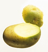 A potato with a greenish skin, a piece cut off