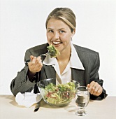 A Woman Eating a Mixed Green Salad