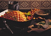 Baked ham with vegetables in roasting dish; knife, pepper