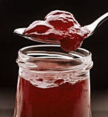 Raw-stirred strawberry jam on spoon over jar