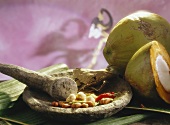 Stillleben mit Nüssen & Gewürzen im Mörser & grüne Kokosnüsse