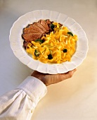 Duck breast slices with ribbon noodles & broccoli on plate