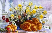 Two Easter bunnies made from dough in front of Easter flower arrangement