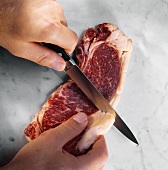 A Knife Removing the Fat From a Steak Before Cooking