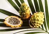Pitahaya, two whole and one half fruit on palm leaf