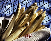White asparagus spears in kitchen cloth on wire rack