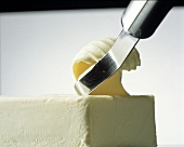 Utensil Slicing a Butter Curl From a Stick of Butter