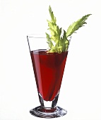 A glass of beetroot juice decorated with celery stick
