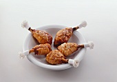 Roast chicken drumsticks with paper frills in deep plate