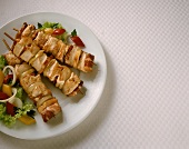 Chicken kebabs with bacon and onions on plate with salad