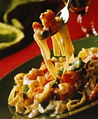 Ribbon noodles with shrimps, creamed vegetables on plate & fork