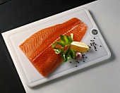 Smoked salmon side on kitchen board, décor: herbs, spices