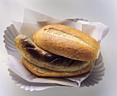 A sausage (Bratwurst) in a roll on paper plate