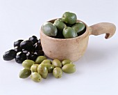 Three different types of olive in & beside wooden scoop