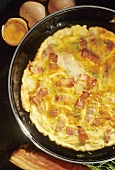 Omelette with bacon and diced ham in frying pan