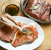 Brushing pork cutlets with herb marinade, roast beef