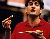 Man in red polo shirt eating frankfurter