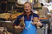 Trader with two crabs in his arms (market hall)