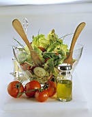 Gemischter Salat in Glasschüssel, Holzbesteck,Tomaten,Öl