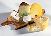 Verschiedene Käsesorten auf rustikalem Holzbrett mit Oregano