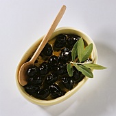 Bottled olives with wooden spoon in bowl
