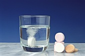 Soluble vitamin tablet in glass & vitamin tablets beside it